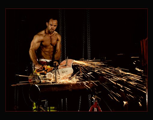 A muscular man using a power tool to throw sparks